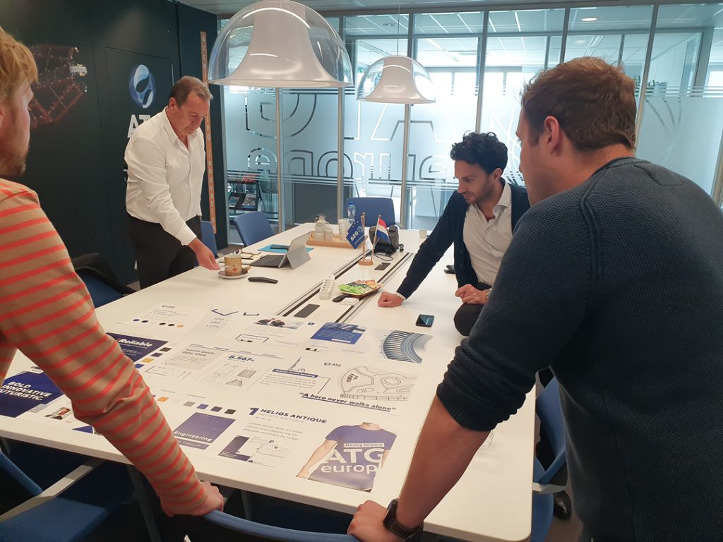 Four professionals collaborating and reviewing design materials at a meeting table in an office with ATG Europe branding in the background.